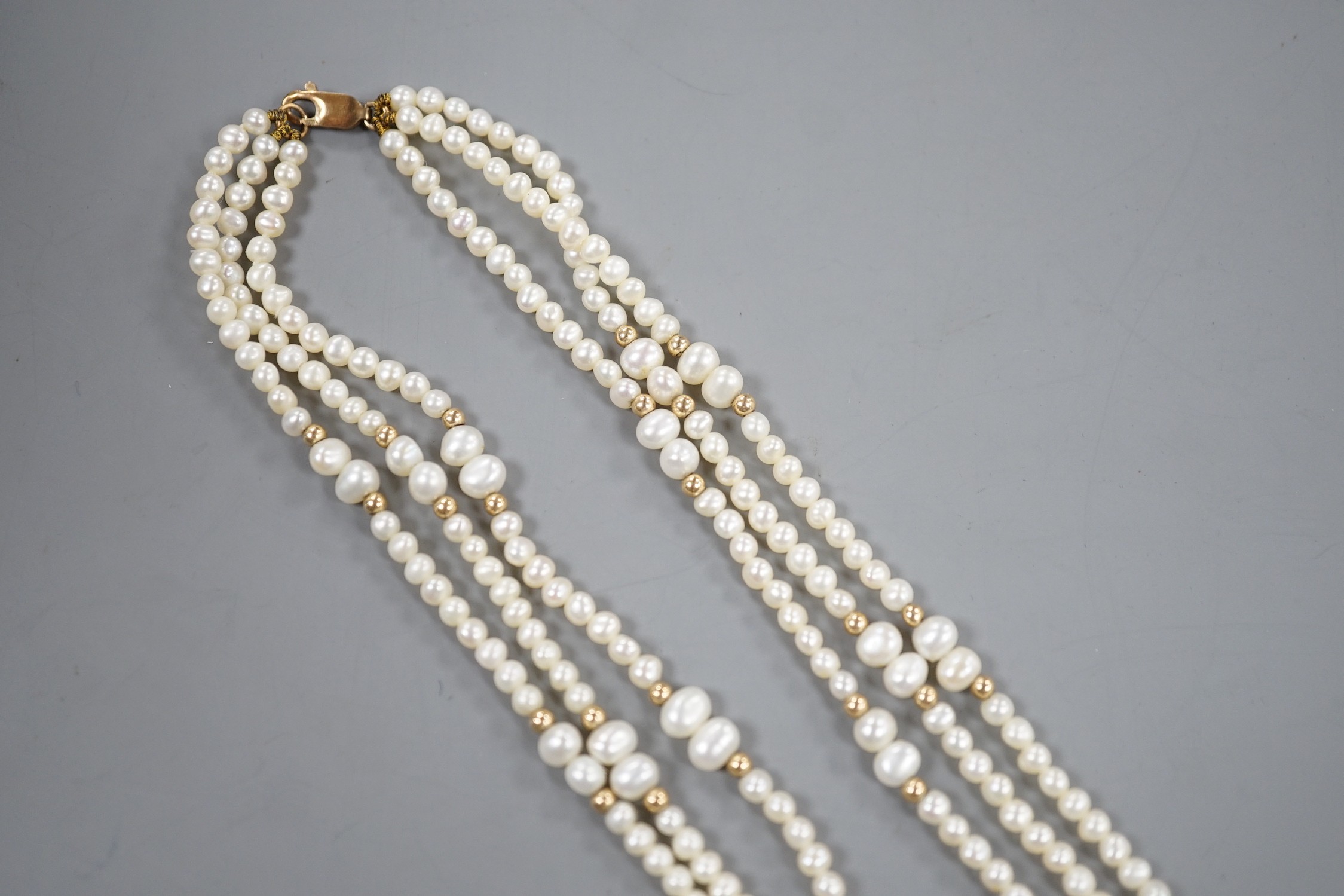 A modern 9k mounted triple strand cultured pearl necklace, 39cm, with yellow metal spacers.